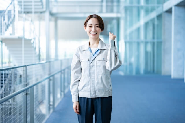 事務所の中でガッツポーズする作業着の女性