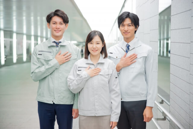 胸に手を当てている、作業着を着た女性1人と男性2人