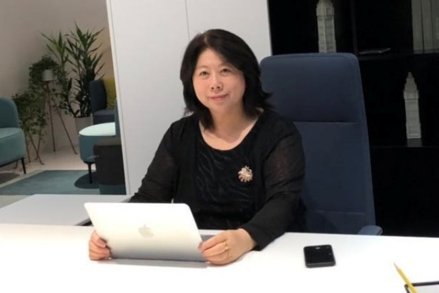 便利屋代表の川崎文子がパソコンを開いてデスクに座っている